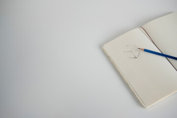 Notebook with a sketch and pencil on a white desk
