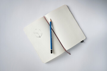 Top view notebook with a sketch and pencil on a white desk