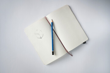 Top view notebook with a sketch and pencil on a white desk