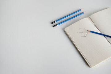 Notebook with a sketch and pencils on a white desk
