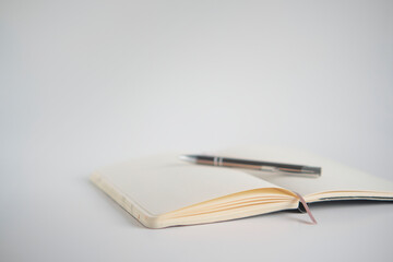 Opened notebook with pen on a white desk