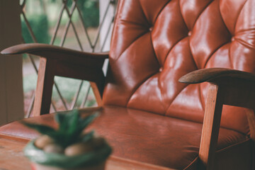 The wooden armrests of the old brown sofa with backrest sit comfortably in the living room. With the morning sun giving a feeling of relaxation on a relaxing day.