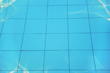 Azure blue swimming pool old tiled floor, sun reflects on ground, underwater photo - abstract holiday background