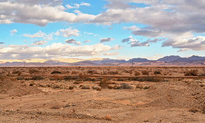 Typical landscape at Israel Jordan border. Flat dry desert with low bushes and small mountains, sun shines through evening clouds