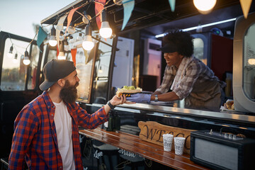 beardy hipster taking sandwich to go from polite female employee in fast food service