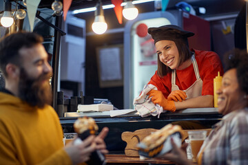 friends socializing with employee in fast food service, eating sandwiches, talking, laughing