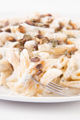Pasta with blue cheese and cream sauce, sprinkled with roasted pumpkin seeds eaten with a fork