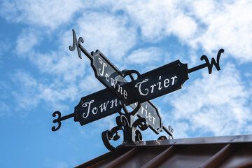 towne crier weathervane sign on the roof of a building with a partly cloudy blue sky