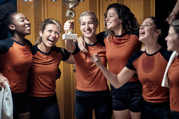 A female team posing and celebrating the won trophy. Female team sport