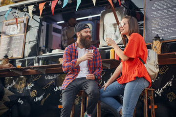 caucasian couple talking, smiling, drinking in front of modified truck for fast food service
