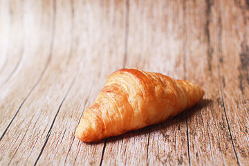 Fresh croissants on a wooden table and on the bamboo basket.