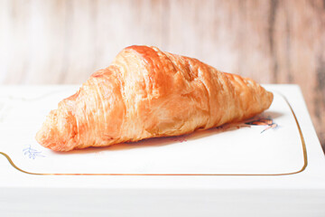 Fresh croissants on a wooden table and on the bamboo basket.