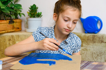 a girl drawing blue gouache cardboard, artistic creation at home, makes creative artwork