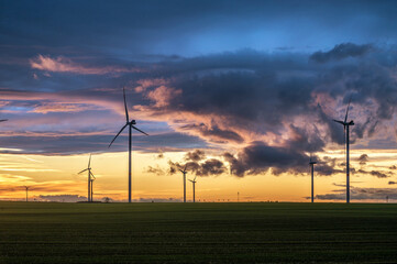 Fototapeta na wymiar Verantwortungsvolle und zukunftsorientierte Stromerzeugung mit modernen Windkraftanlagen auf einem Feld im Sonnenuntergang