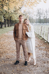 Fototapeta premium Beautiful young couple in autumn walks with dogs, pomeranian, in the park