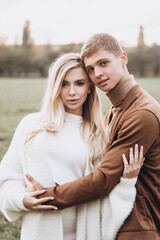 Fototapeta premium Beautiful young couple in autumn walks with dogs, pomeranian, in the park
