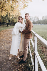 Beautiful young couple in autumn walks with dogs, pomeranian, in the park