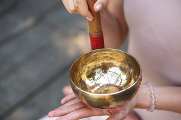 Meditation with vibrations from the bowl in the lotus position. Nature yoga theme hands and bronze...