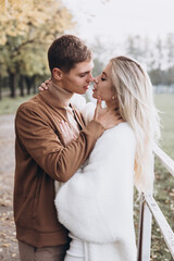 Beautiful young couple in autumn walks with dogs, pomeranian, in the park