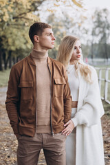 Fototapeta premium Beautiful young couple in autumn walks with dogs, pomeranian, in the park