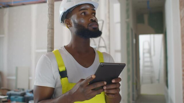 African architect inside house being renovated using digital tablet