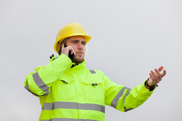 Young engineer or worker with green protective work wear talking on mobile phone