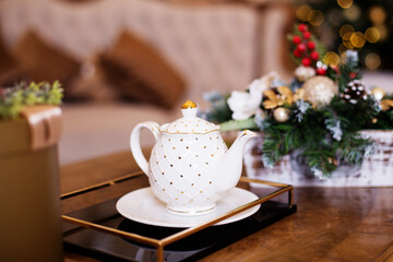 White teapot for making tea on the table, against the background of a Christmas tree. Tea ceremony. New year's concept 2021