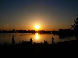 Naklejka na ściany i meble Three Men Fishing in the Lake Underneath the Sunset