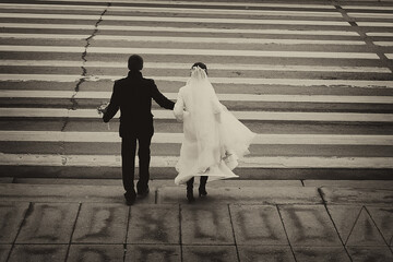 Conceptual symbolic photography. At the crosswalk, the bride in white, the groom in black. Metaphor of the beginning, the transition from one state to another, black and white stripes i