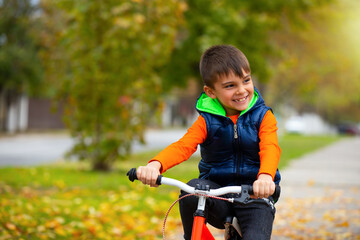 Fototapeta na wymiar Happy child. Boy on a bike in a city park. The concept of relaxation and fun time. Photo with empty space