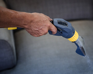 hand with a vacuum cleaning couch