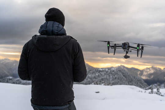 Drone Pilot Flies DJI Inspire 2 Over Snowy Mountains at Sunrise