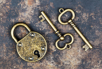 Escape room game concept, old vintage keys and a padlock on rusty grunge metal background