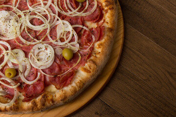 Pepperoni pizza, slices of onions, mozzarella cheese and green olives. Top close-up photograph. Right space for texts.
