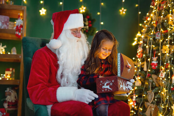Fototapeta na wymiar Santa Claus with a little cute girl open magical gift box in the room. Christmas time.