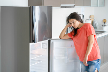 The girl is surprised at the empty refrigerator. Lack of food. Food delivery