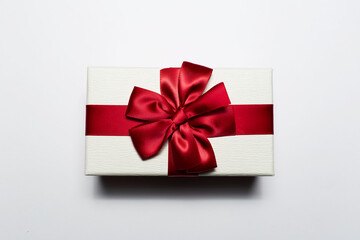 Close-up of Christmas gift box of white color with red bow, isolated on white background.