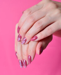 female hands with painted nails on pink background.