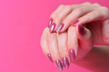 female hands with painted nails on pink background.