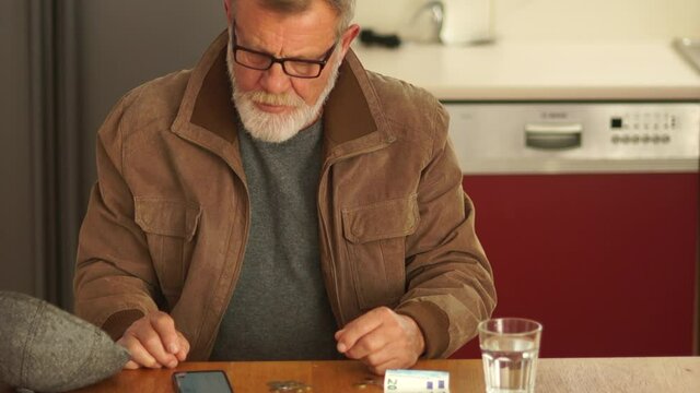 Man who has lost his job considers a trifle while sitting in the kitchen during the economic crisis. Social benefits for layoffs. Unemployment and utility bills concept