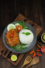 Ayam geprek, Indonesian popular streed food, made from crispy chicken smashed with sambal or chili sauce, eat with rice and cucumber, lettuce, tomato and kemangi. Isolated background, copy space.