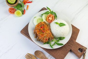 Ayam geprek, Indonesian popular streed food, made from crispy chicken smashed with sambal or chili sauce, eat with rice and cucumber, lettuce, tomato and kemangi. Isolated background, copy space.