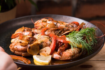 Delicious fried langoustines in sauce on a black plate, prepared in an Asian style. Fast and ready meal concept