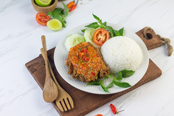 Ayam geprek, Indonesian popular streed food, made from crispy chicken smashed with sambal or chili sauce, eat with rice and cucumber, lettuce, tomato and kemangi. Isolated background, copy space.