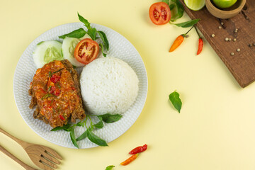 Ayam geprek, Indonesian popular streed food, made from crispy chicken smashed with sambal or chili sauce, eat with rice and cucumber, lettuce, tomato and kemangi. Isolated background, copy space.