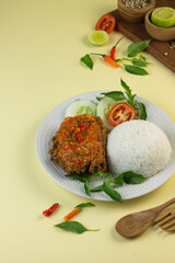 Ayam geprek, Indonesian popular streed food, made from crispy chicken smashed with sambal or chili sauce, eat with rice and cucumber, lettuce, tomato and kemangi. Isolated background, copy space.