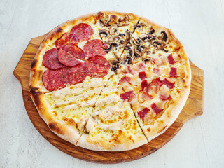 Assotri pizza with sausage, mushrooms, bacon and chicken meat lies on a wooden tray