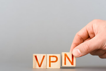 vpn. man folds from wooden blocks the inscription vpn on a gray background