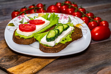 sandwich with cheese, lettuce and tomato on a wooden table