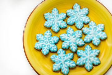 Christmas ginger cookies in the form of blue snowflakes on a yellow plate